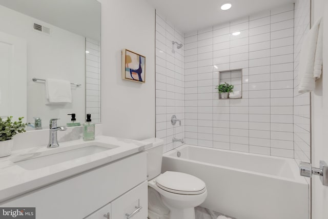 full bathroom featuring vanity, tiled shower / bath combo, and toilet