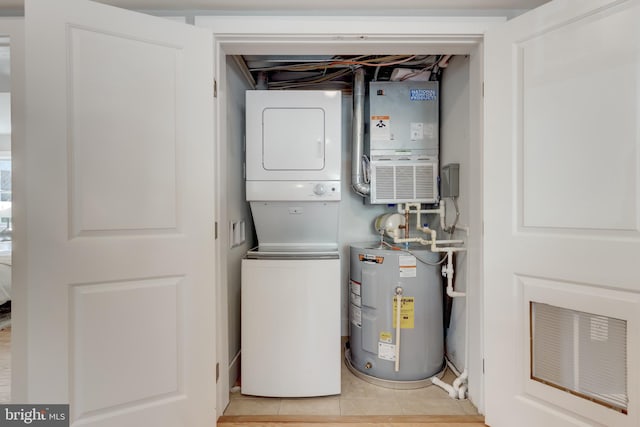 utility room featuring electric panel, water heater, and stacked washing maching and dryer