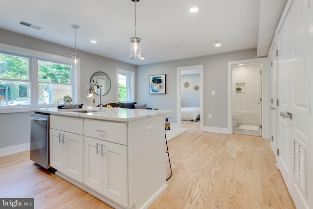 kitchen with light hardwood / wood-style flooring, pendant lighting, a kitchen island with sink, white cabinetry, and dishwasher