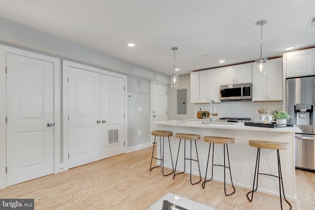 kitchen featuring light hardwood / wood-style floors, decorative light fixtures, and appliances with stainless steel finishes