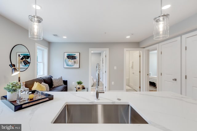 kitchen featuring sink, pendant lighting, and light stone counters