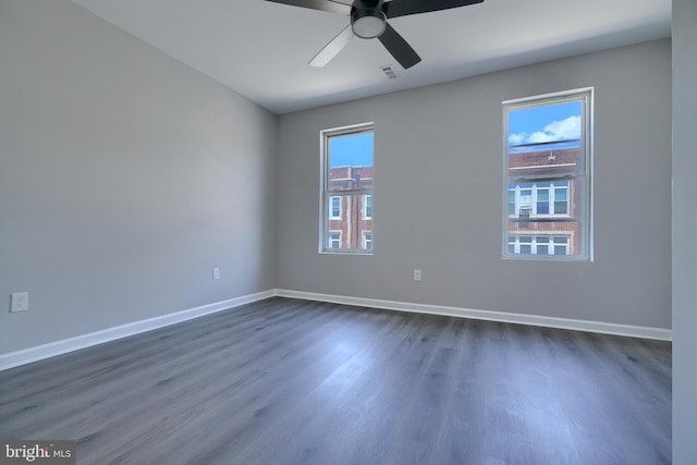 spare room with ceiling fan, a healthy amount of sunlight, and dark hardwood / wood-style floors