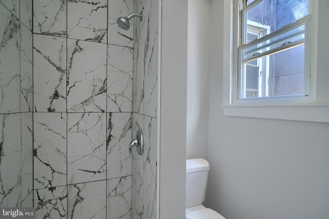 bathroom with a tile shower and toilet