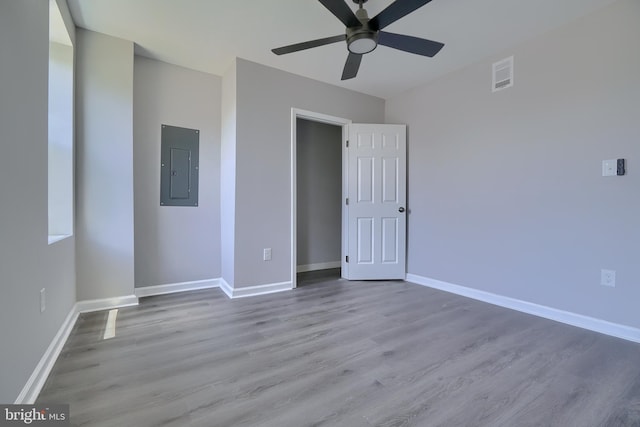 unfurnished bedroom with a closet, electric panel, ceiling fan, and light hardwood / wood-style flooring