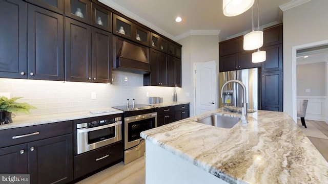 kitchen with pendant lighting, light stone counters, ornamental molding, and premium range hood