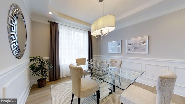 dining space featuring a raised ceiling, ornamental molding, a wealth of natural light, and light hardwood / wood-style flooring