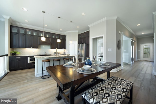 dining area with light hardwood / wood-style flooring and ornamental molding