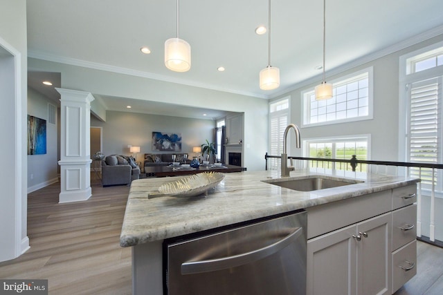 kitchen featuring a center island with sink, dishwasher, light stone countertops, and sink