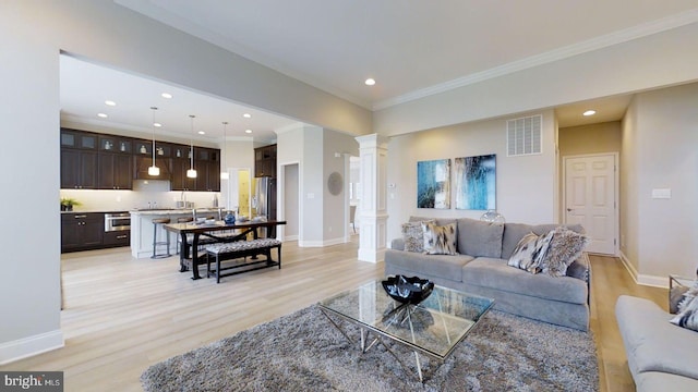 living room with light wood-type flooring, ornate columns, and ornamental molding