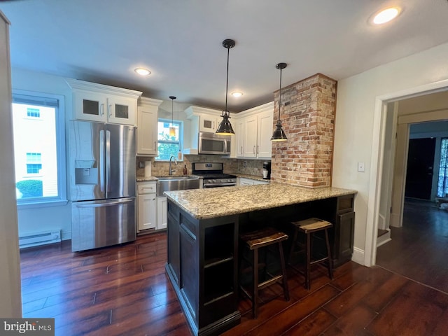 kitchen featuring a baseboard heating unit, white cabinets, hanging light fixtures, tasteful backsplash, and stainless steel appliances