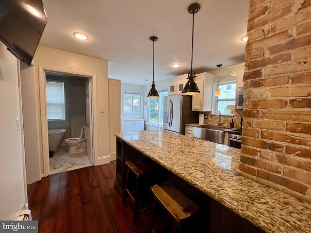 kitchen featuring white cabinets, light stone countertops, stainless steel appliances, and hanging light fixtures