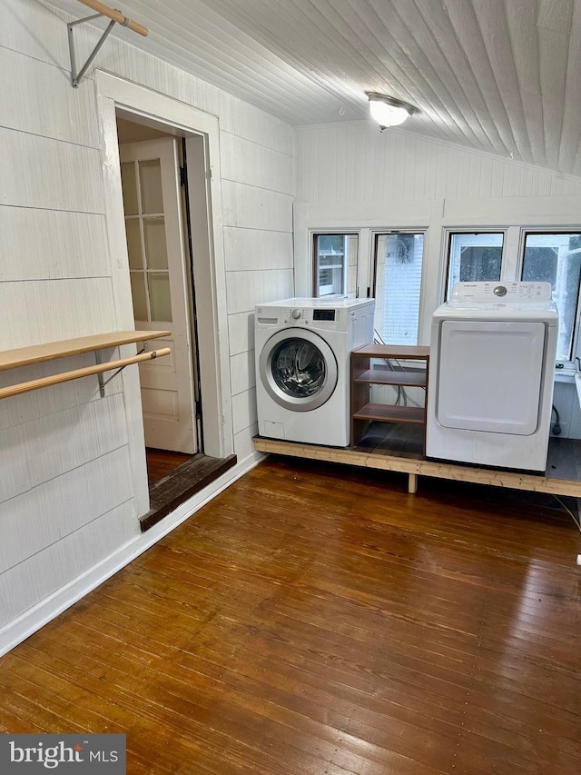 laundry area with hardwood / wood-style floors, washer and clothes dryer, and wooden walls