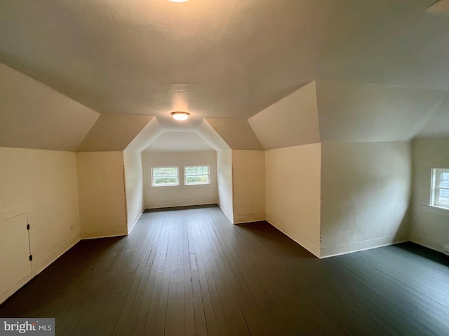 additional living space with dark wood-type flooring and vaulted ceiling