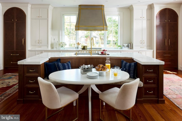 kitchen featuring breakfast area, a center island with sink, dark hardwood / wood-style floors, and a healthy amount of sunlight