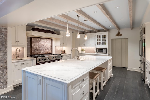 kitchen with appliances with stainless steel finishes, sink, white cabinetry, and an island with sink