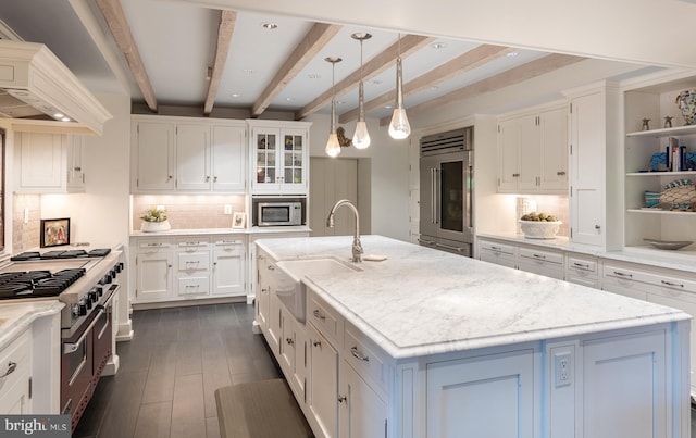 kitchen with backsplash, a kitchen island with sink, decorative light fixtures, white cabinetry, and stainless steel appliances