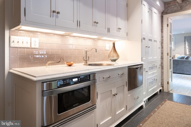 kitchen with backsplash, dark tile patterned floors, sink, white cabinetry, and oven