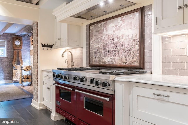 kitchen featuring backsplash, custom range hood, dark wood-type flooring, range with two ovens, and white cabinets