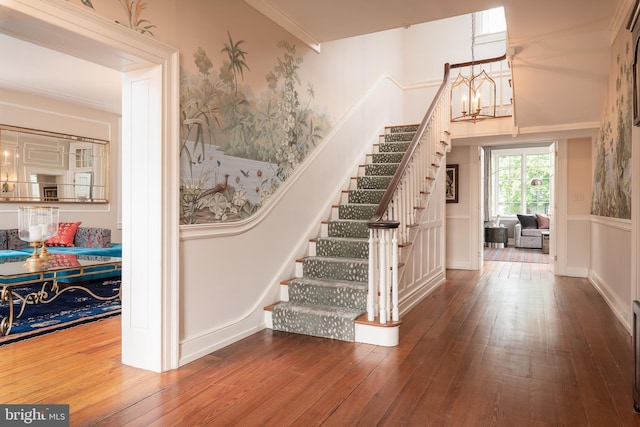 stairs with a chandelier, hardwood / wood-style floors, and crown molding