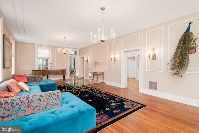 living room with hardwood / wood-style floors, crown molding, and a notable chandelier