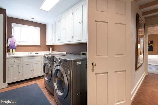 washroom with cabinets, independent washer and dryer, and sink