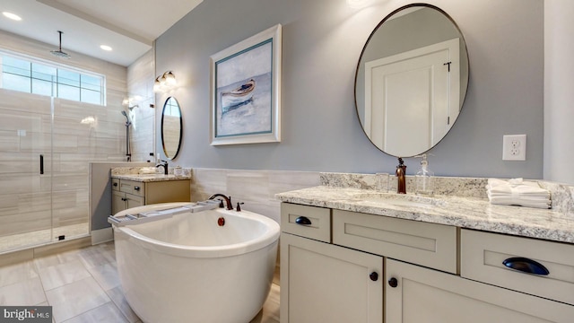 bathroom featuring shower with separate bathtub, vanity, tile walls, and tile patterned floors