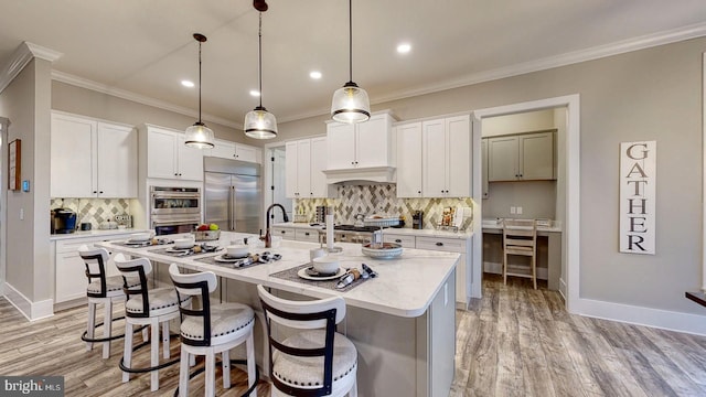 kitchen featuring appliances with stainless steel finishes, white cabinetry, pendant lighting, and an island with sink