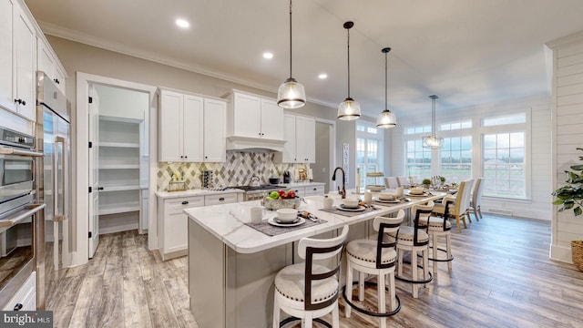 kitchen with white cabinets, decorative light fixtures, and light hardwood / wood-style floors