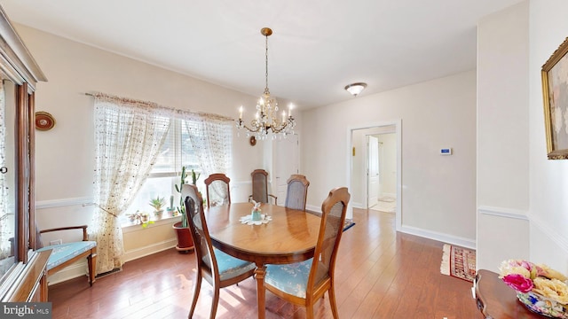 dining space featuring hardwood / wood-style floors and an inviting chandelier