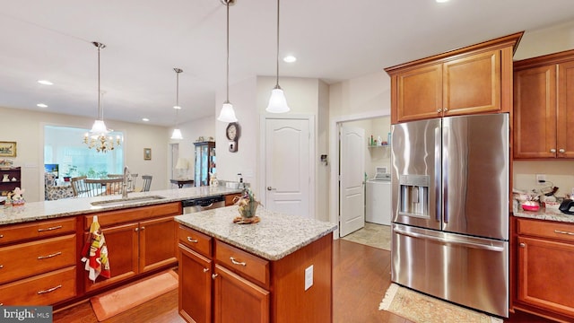 kitchen with stainless steel appliances, sink, decorative light fixtures, light hardwood / wood-style flooring, and a kitchen island