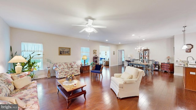 living room with ceiling fan with notable chandelier and dark hardwood / wood-style floors