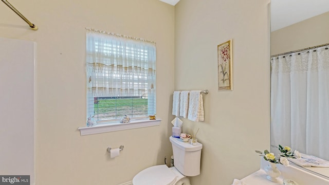 bathroom with a healthy amount of sunlight, toilet, and curtained shower