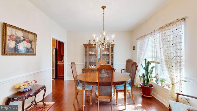 dining room with dark hardwood / wood-style flooring and an inviting chandelier