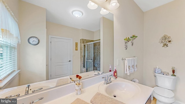 bathroom featuring toilet, a shower with shower door, and sink