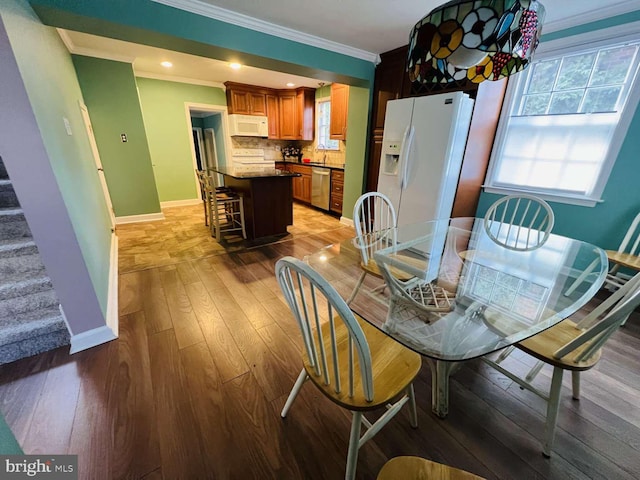 dining area featuring light wood-type flooring, ornamental molding, and a wealth of natural light