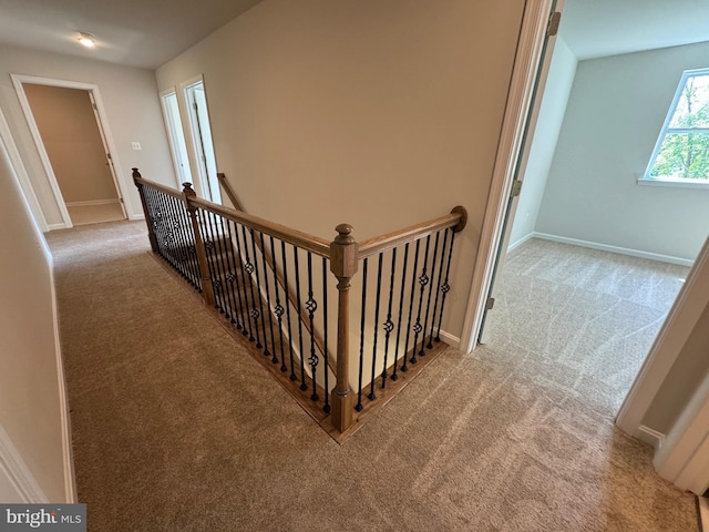 corridor with light carpet, baseboards, and an upstairs landing