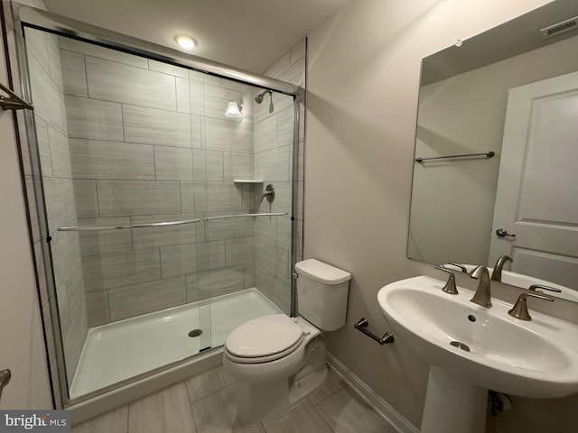 full bath featuring toilet, a sink, visible vents, and a shower stall