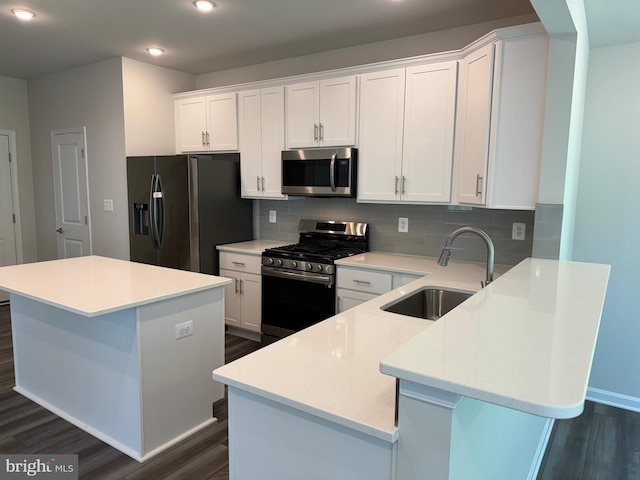 kitchen with a kitchen island, white cabinetry, stainless steel appliances, and a sink