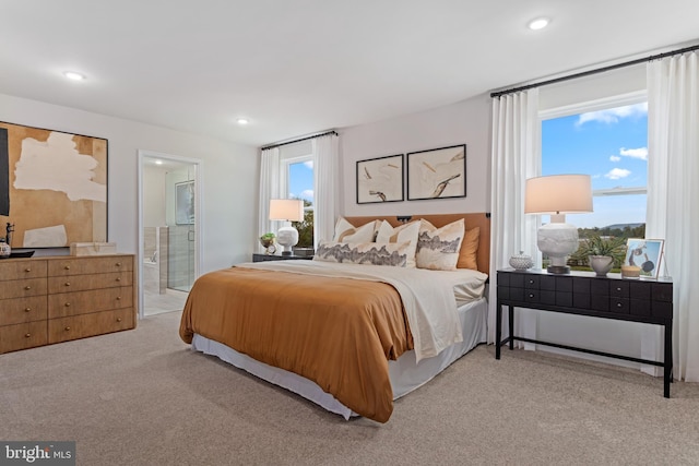 bedroom with recessed lighting, connected bathroom, and light colored carpet