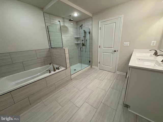 bathroom with double vanity, a stall shower, baseboards, a bath, and a sink