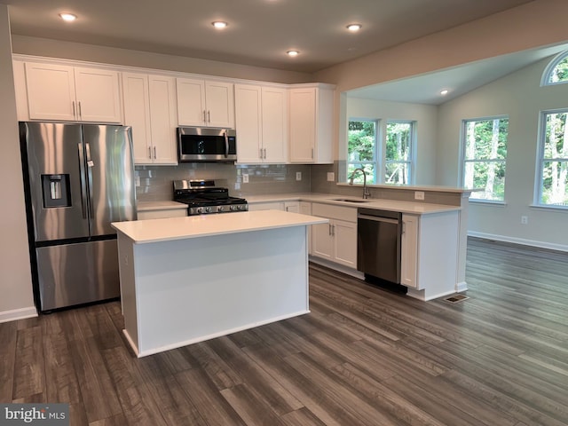 kitchen with sink, a kitchen island, lofted ceiling, and appliances with stainless steel finishes