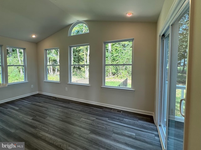 empty room with dark wood-type flooring, a healthy amount of sunlight, vaulted ceiling, and baseboards