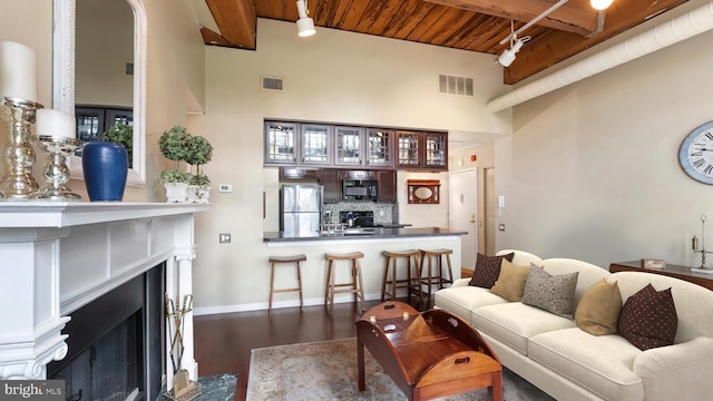 living room with beam ceiling, wood ceiling, dark wood-type flooring, and a towering ceiling