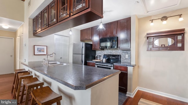 kitchen featuring appliances with stainless steel finishes, backsplash, sink, dark hardwood / wood-style floors, and a breakfast bar area