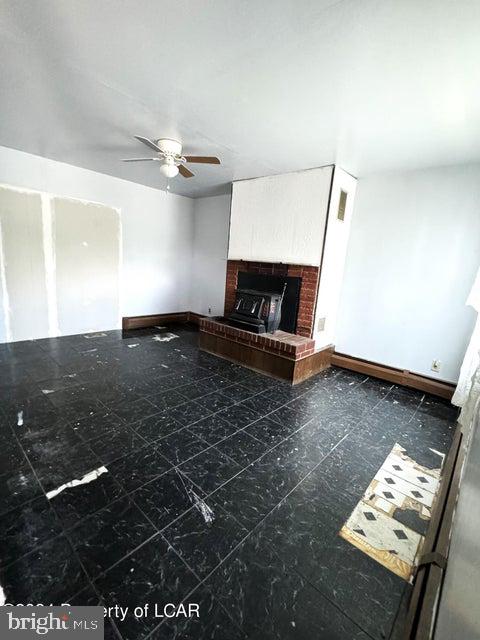 unfurnished living room with ceiling fan and a fireplace