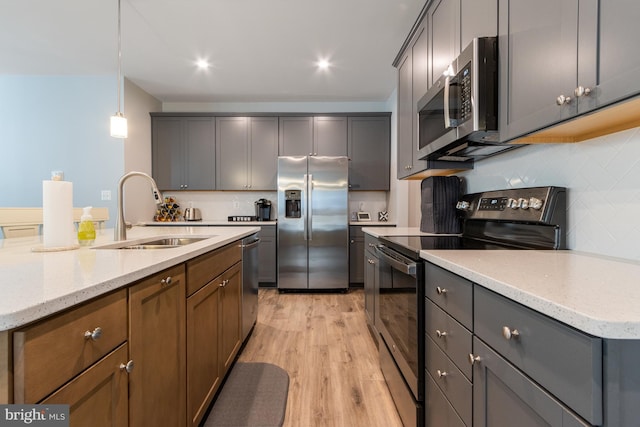 kitchen with pendant lighting, stainless steel appliances, light hardwood / wood-style floors, sink, and decorative backsplash