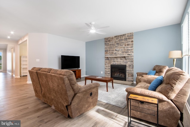 living room featuring a fireplace, light hardwood / wood-style floors, and ceiling fan