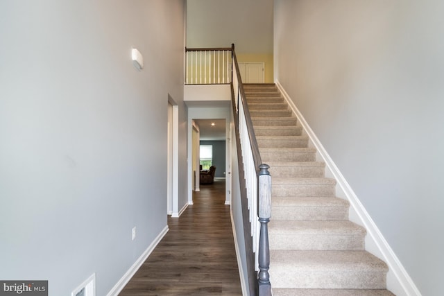 stairs with hardwood / wood-style floors and a towering ceiling