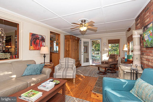 living room with ceiling fan, wood-type flooring, and brick wall