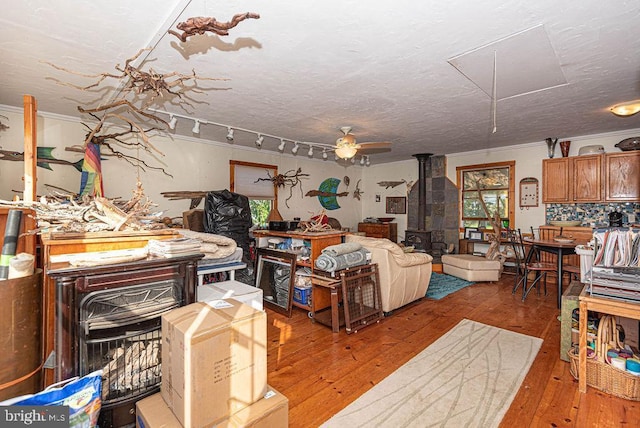 living room featuring hardwood / wood-style floors, ceiling fan, a wood stove, and track lighting